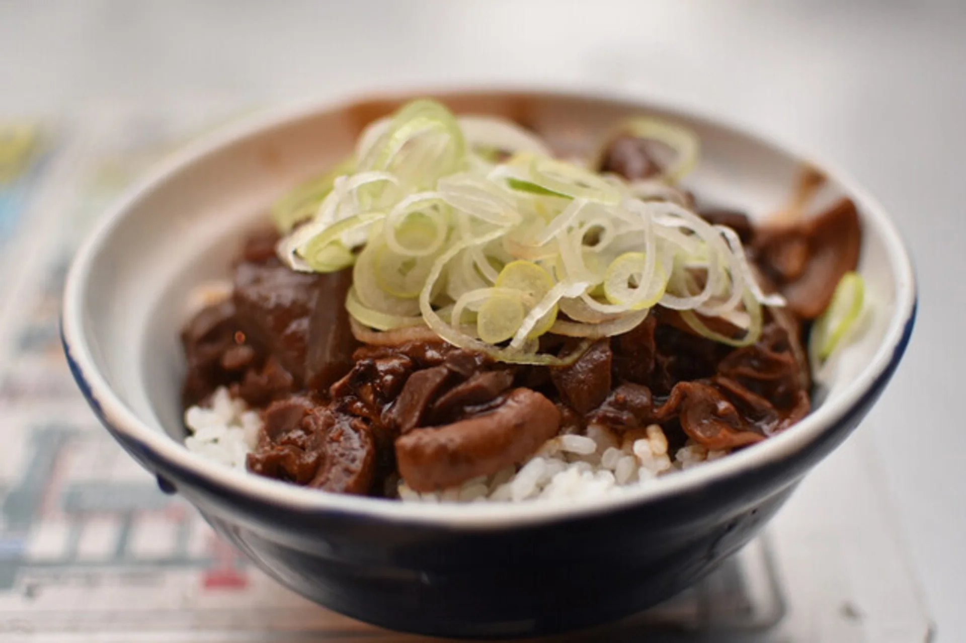八丁味噌で煮込んだ牛ホルモンの丼、葱をのせて